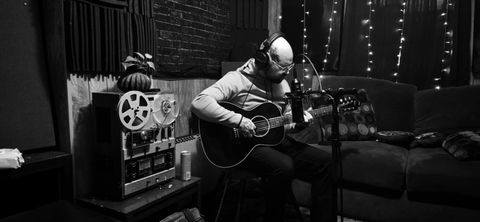 Brando recording acoustic guitar beside a reel-to-reel tape machine